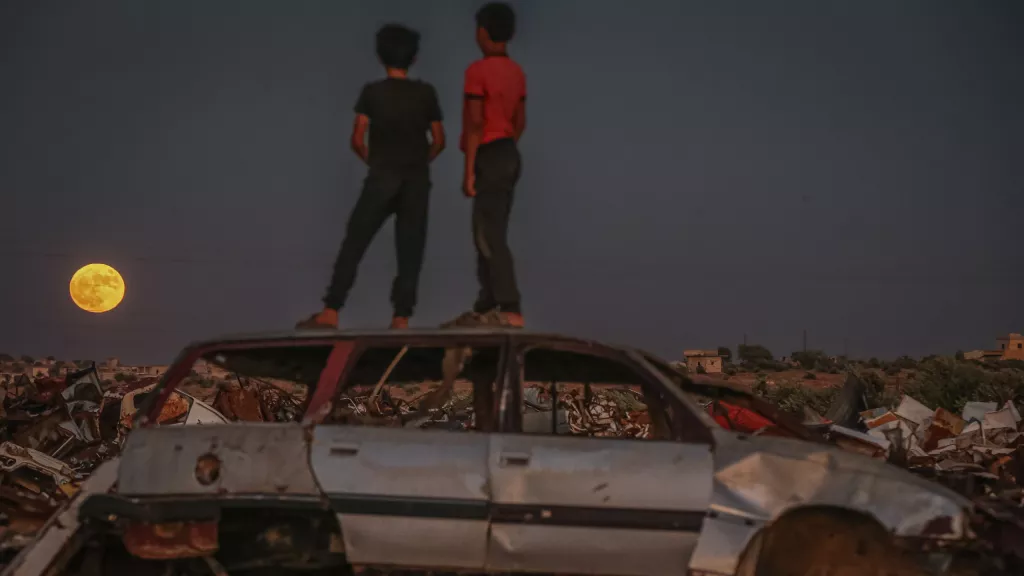 伊德利卜,孩子们坐在废旧汽车上观看升起的超级月亮。图片来源: Muhammed Said/Anadolu Agency via Getty Images